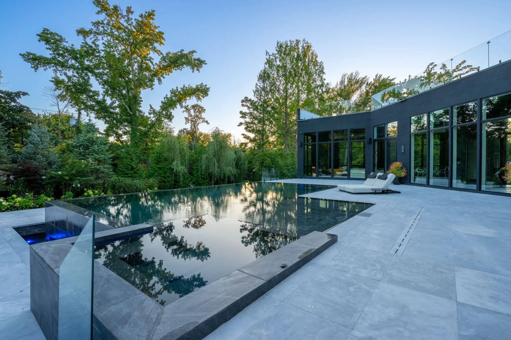 Dark Kings Point pool and attached spa beside a modern residence with glazing
